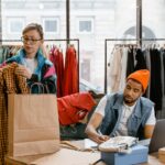 Retail workers organizing clothing in a boutique setting, fostering teamwork.